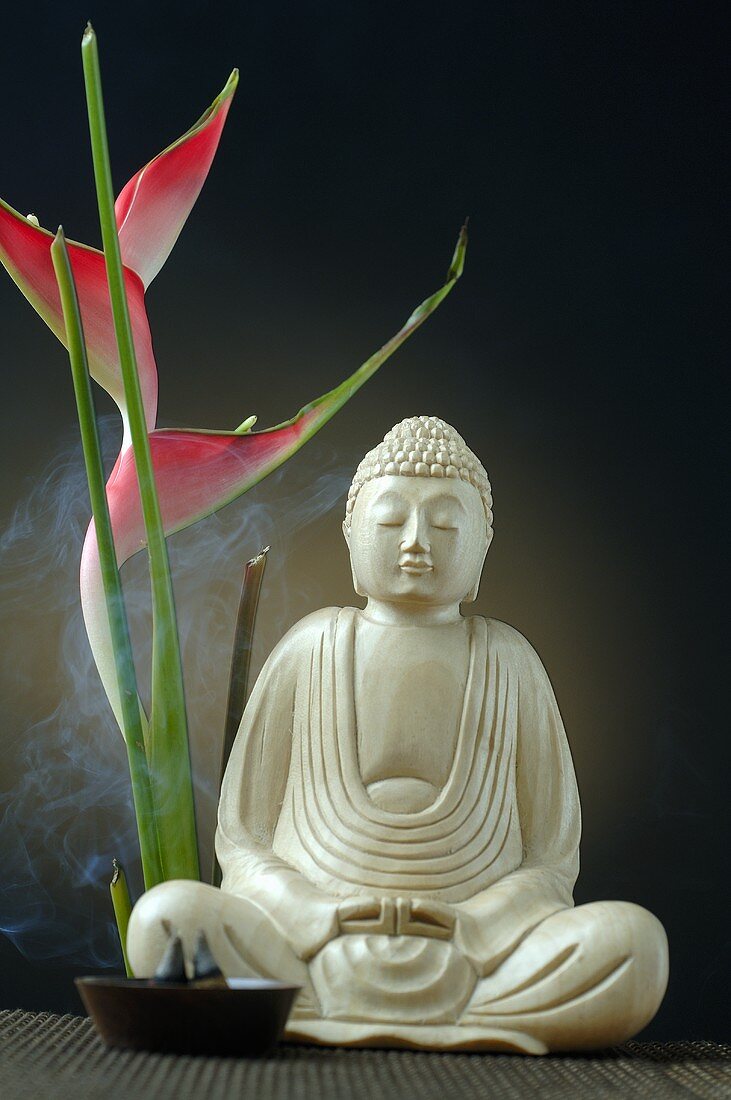 Buddhafigur mit Räucherstäbchen und Paradiesvogelblume