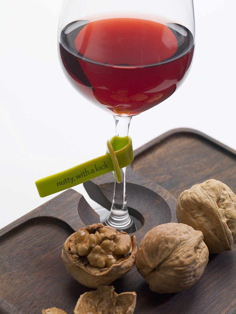 Rotweinglas mit Plastiketikett (Weinbeschreibung) und Nüsse
