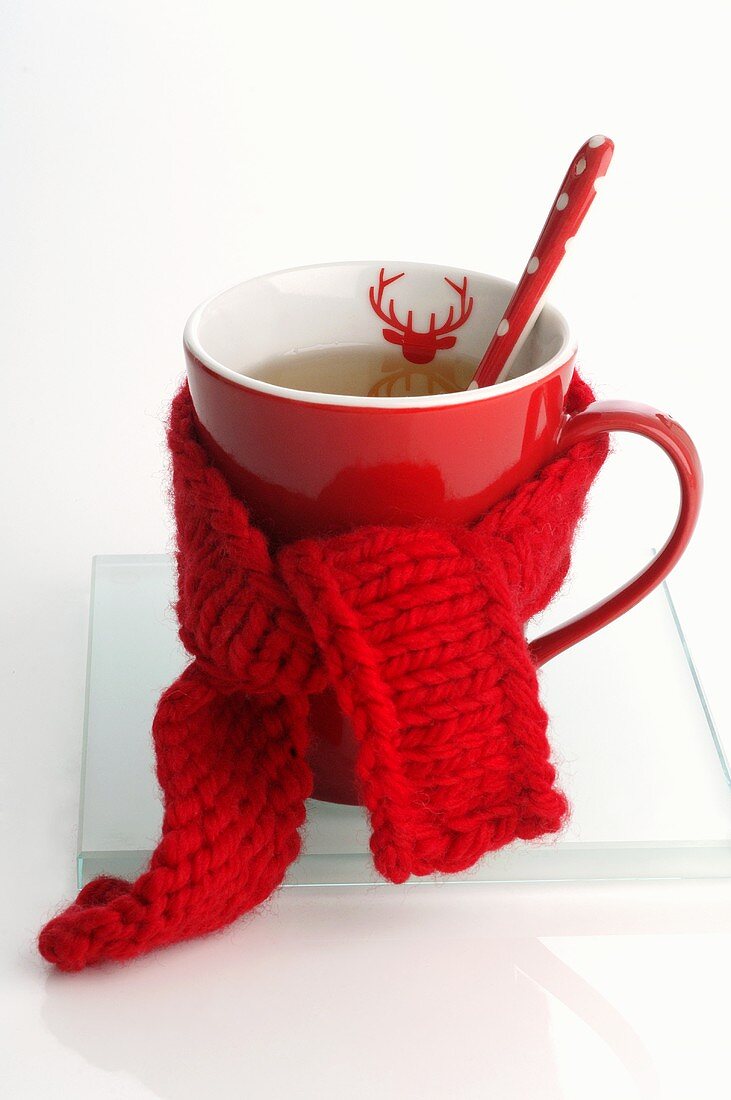 Festive mug of tea with knitted scarf