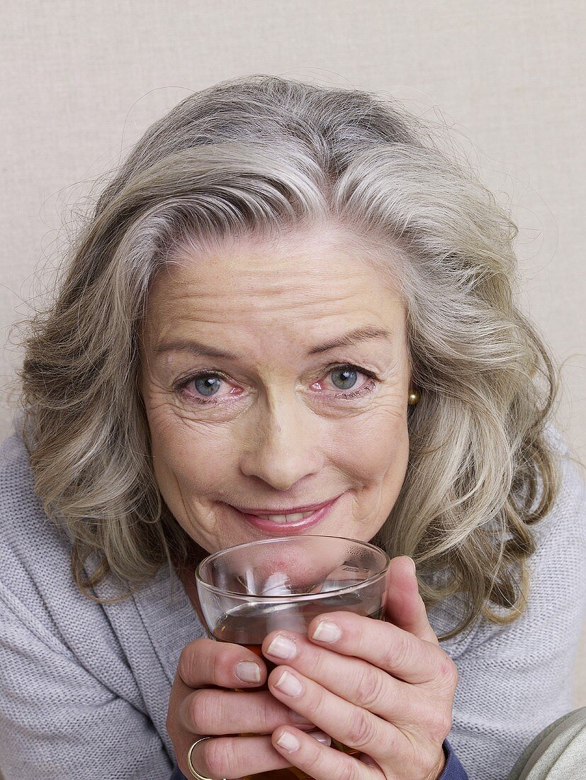 Ältere Frau hält Glas Tee
