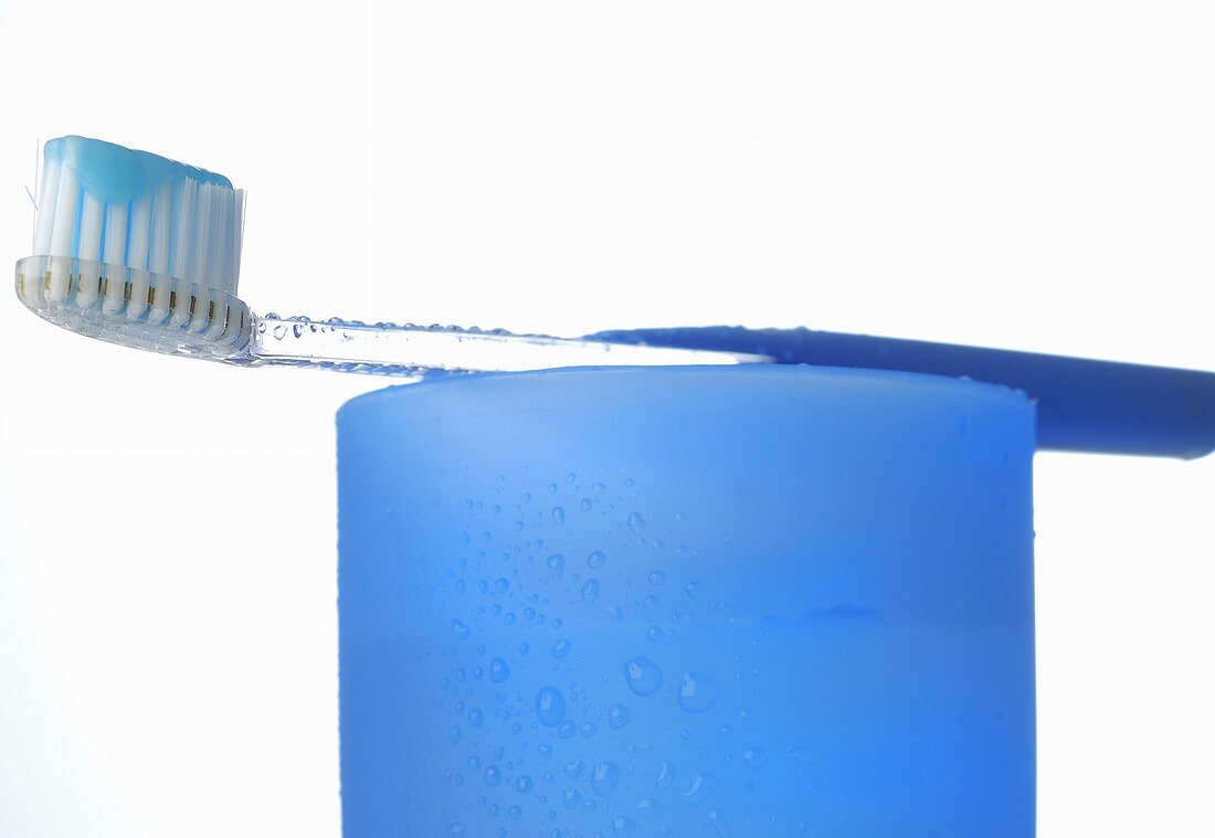 Toothbrush with toothpaste on blue beaker