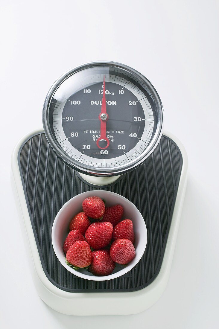 Bowl of fresh strawberries on scales
