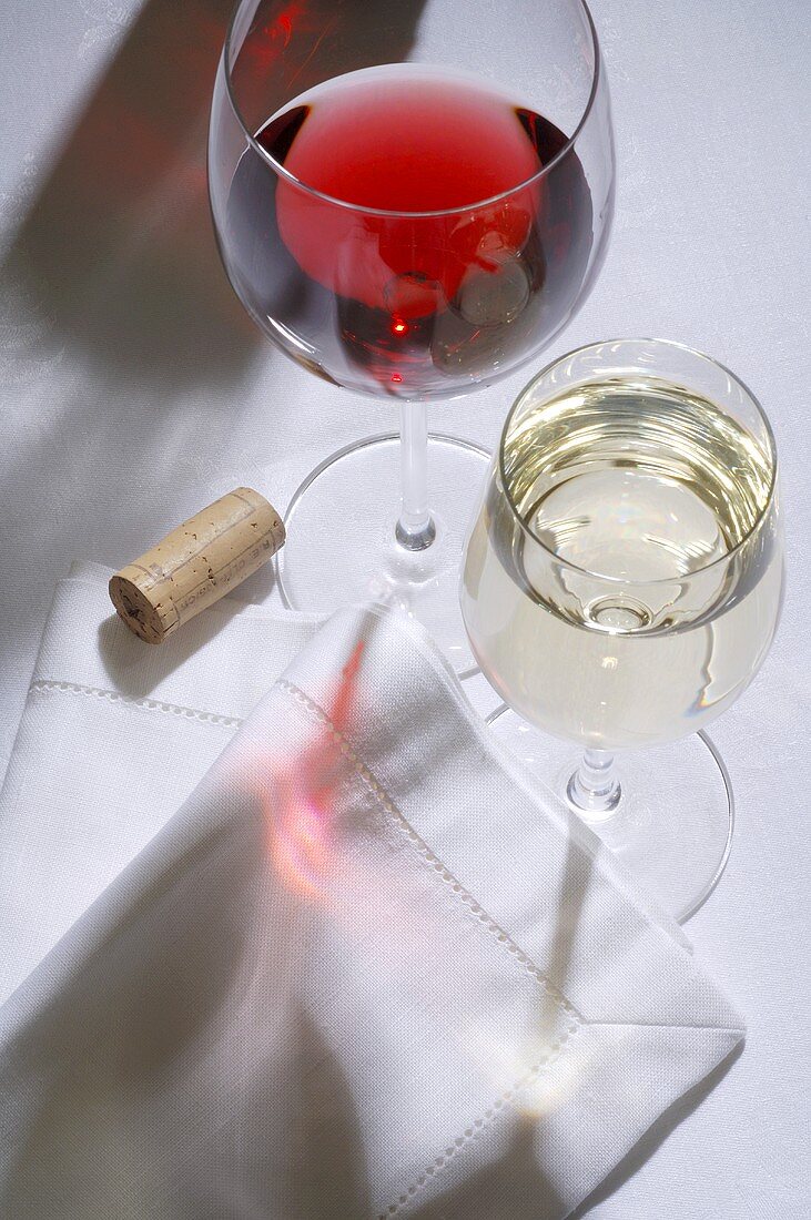 Glass of red wine, glass of white wine, fabric napkin, wine cork