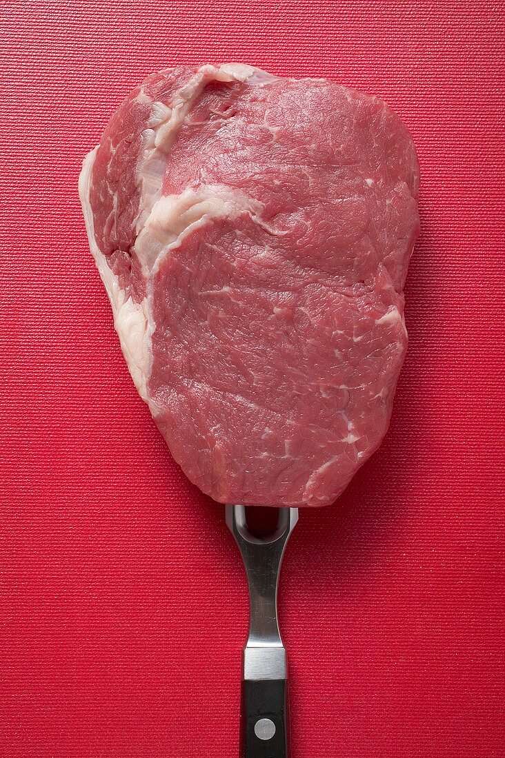 Raw beef steak on meat fork