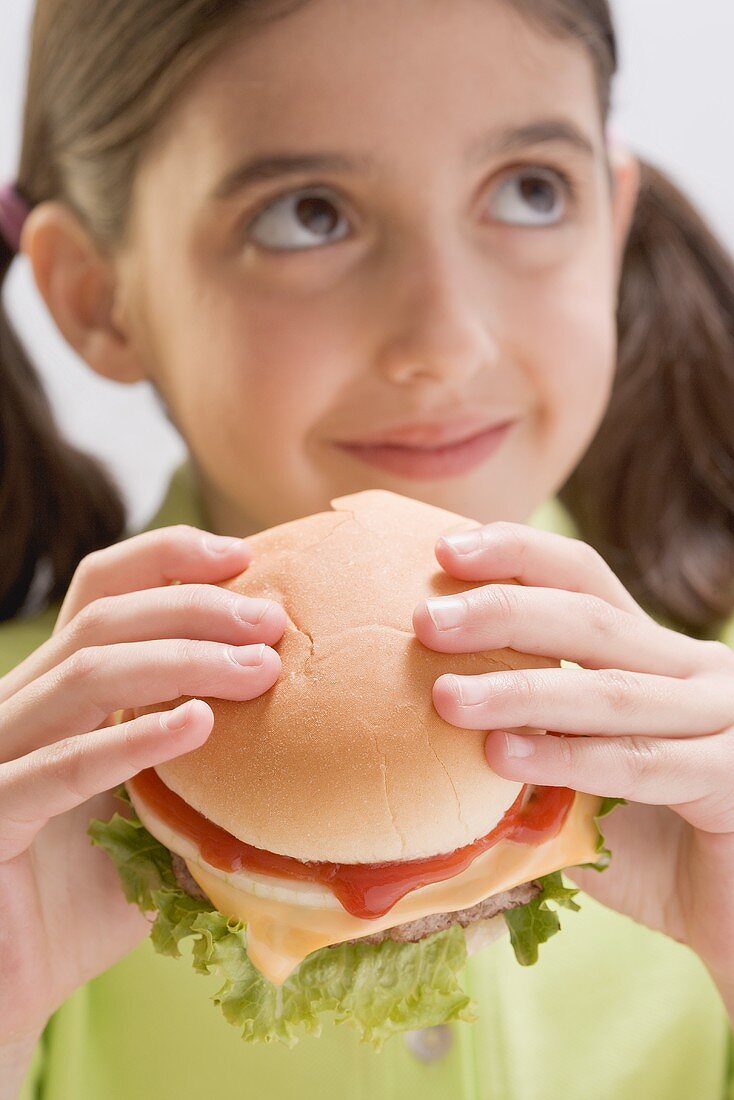 Kleines Mädchen hält Cheeseburger