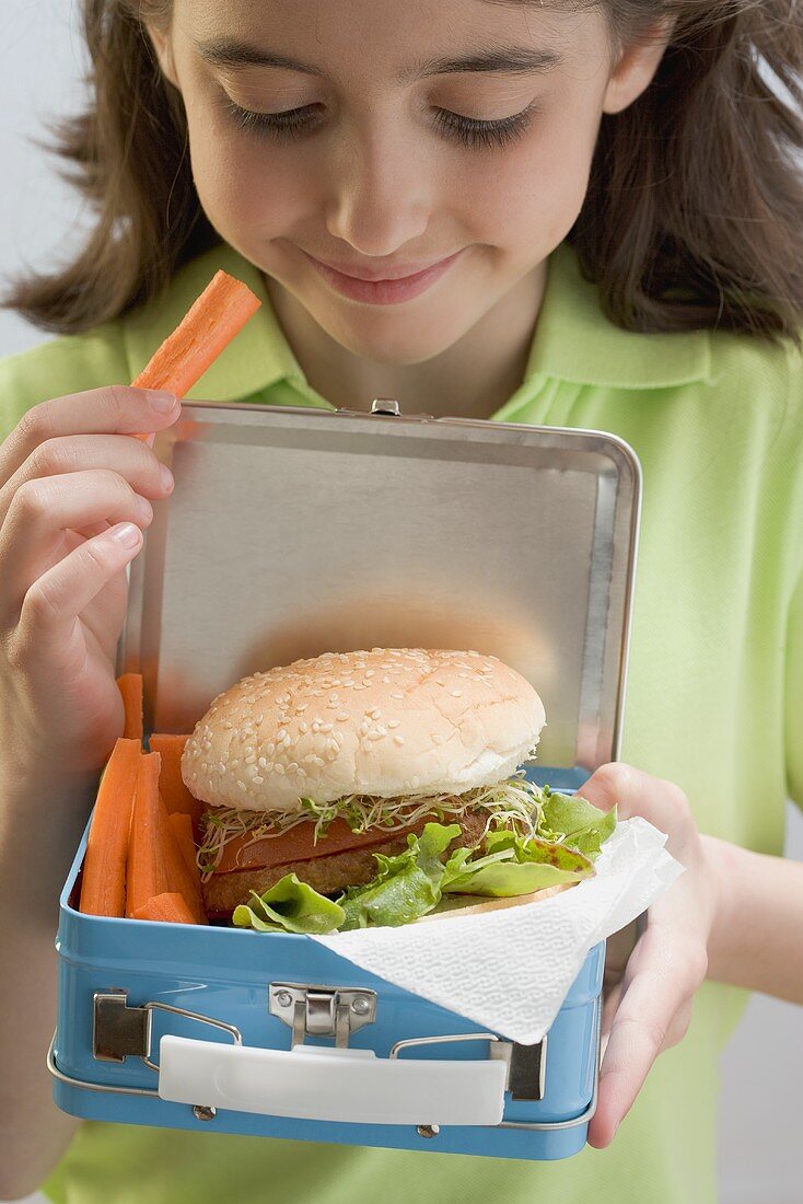 Mädchen hält Lunchbox mit Burger und Möhren