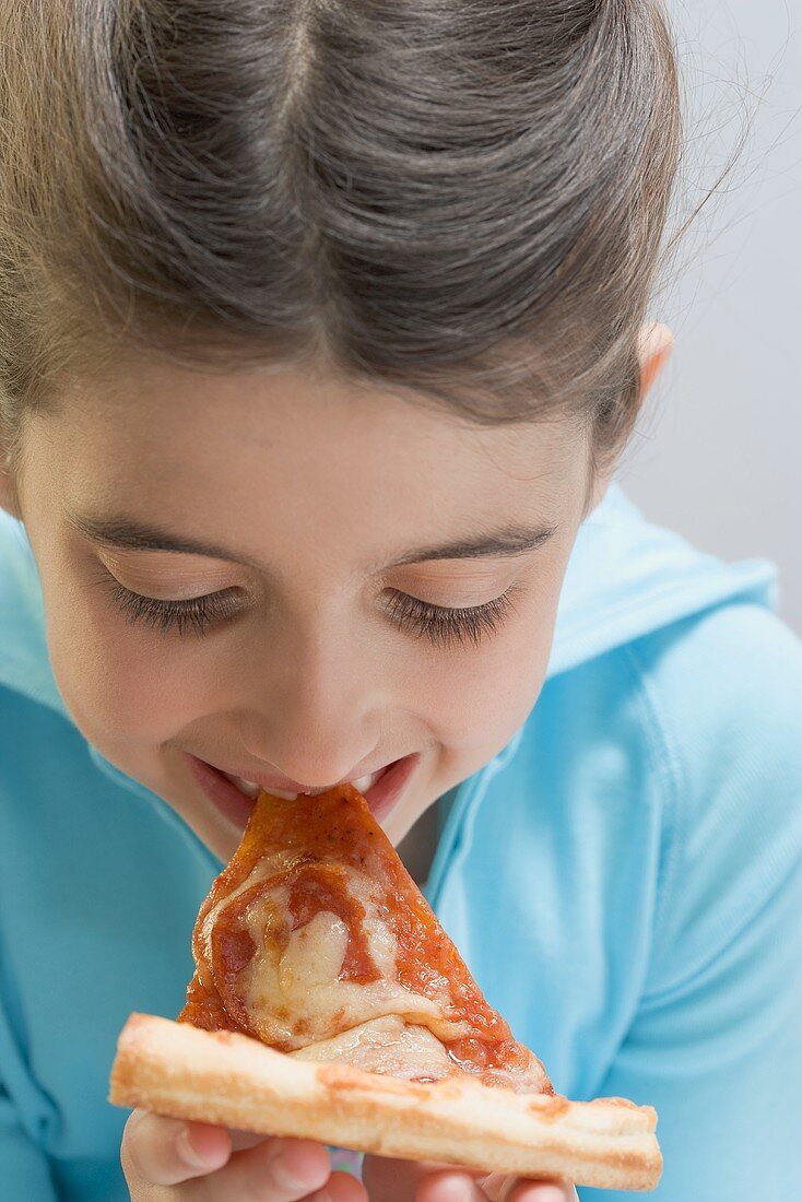 Little girl eating slice of pizza