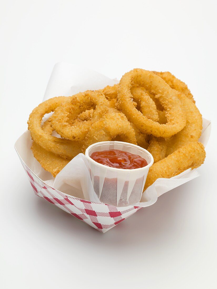 Frittierte Zwiebelringe mit Ketchup im Pappschälchen