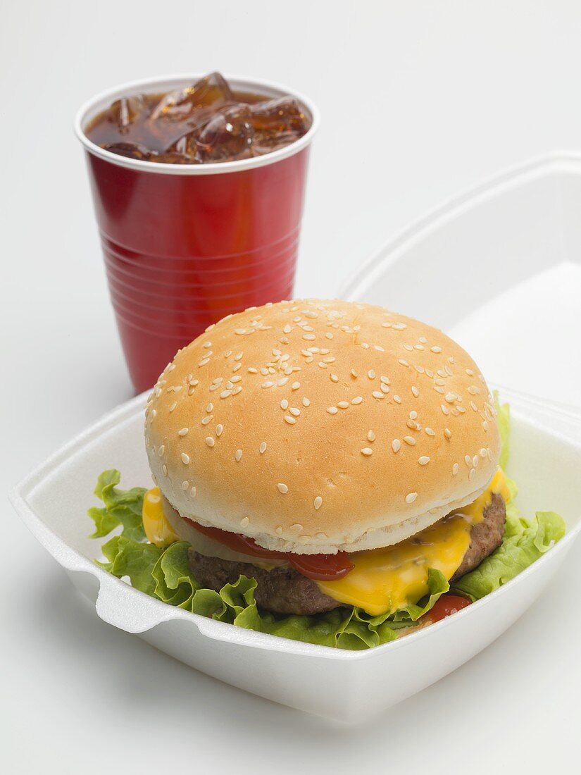 Cheeseburger in Verpackung, Cola im Plastikbecher