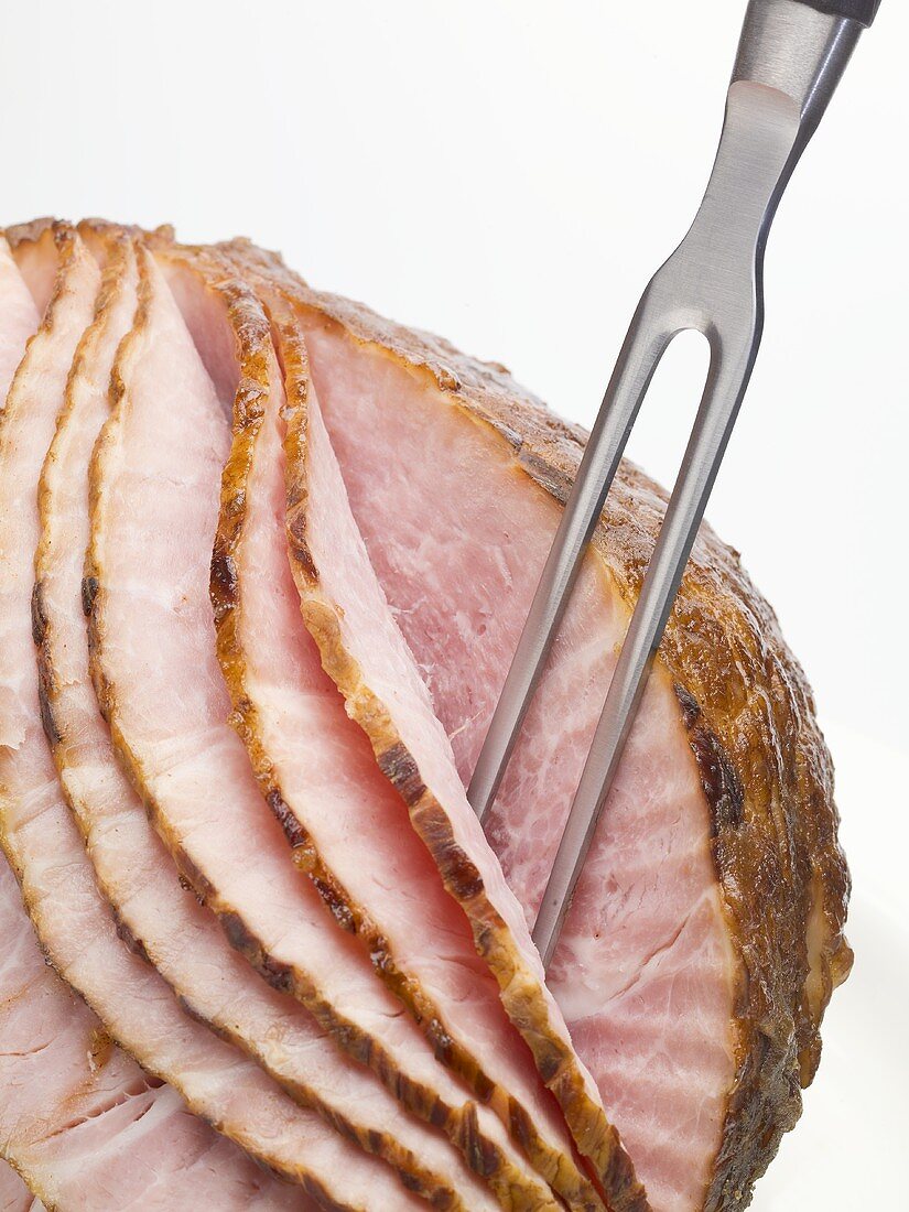 Roast ham, partly carved, with carving fork