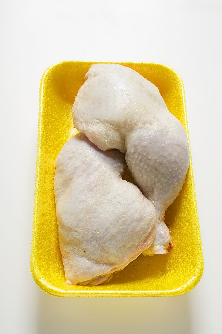 Two fresh chicken legs in polystyrene tray