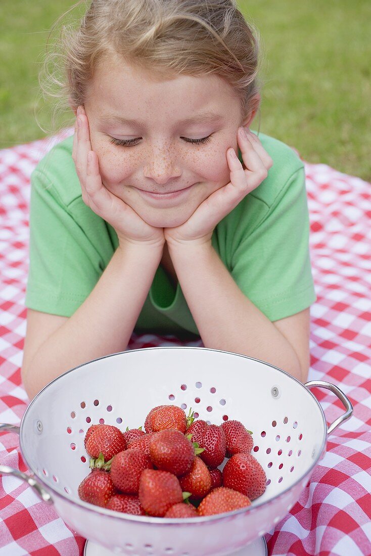 Girl looking at strawberries in colander