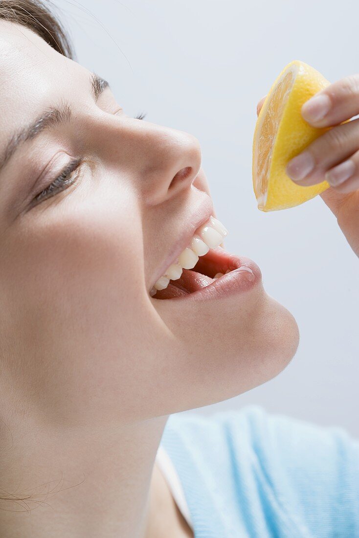 Junge Frau träufelt Zitronensaft auf ihre Lippe
