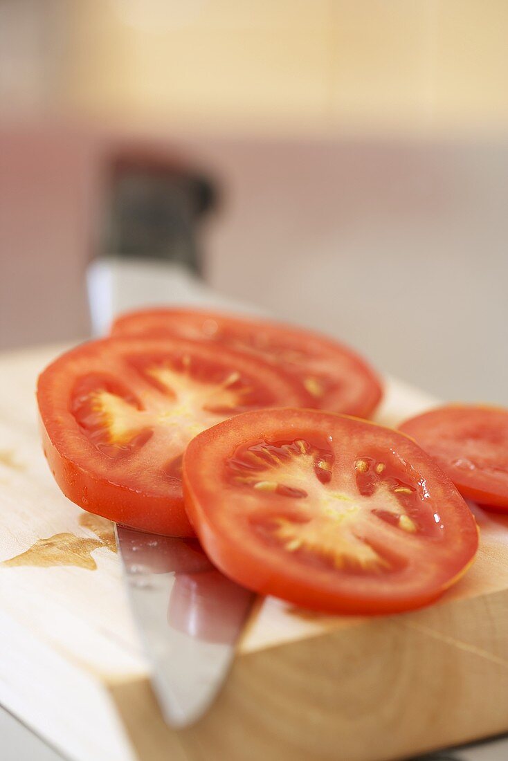 Tomatenscheiben auf Schneidebrett mit Messer
