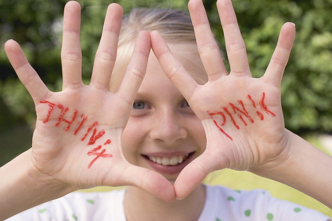 Mädchen zeigt ihre Hände mit Aufschrift THINK PINK