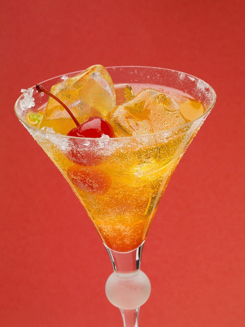 Tequila Sunrise with ice cubes and cocktail cherries