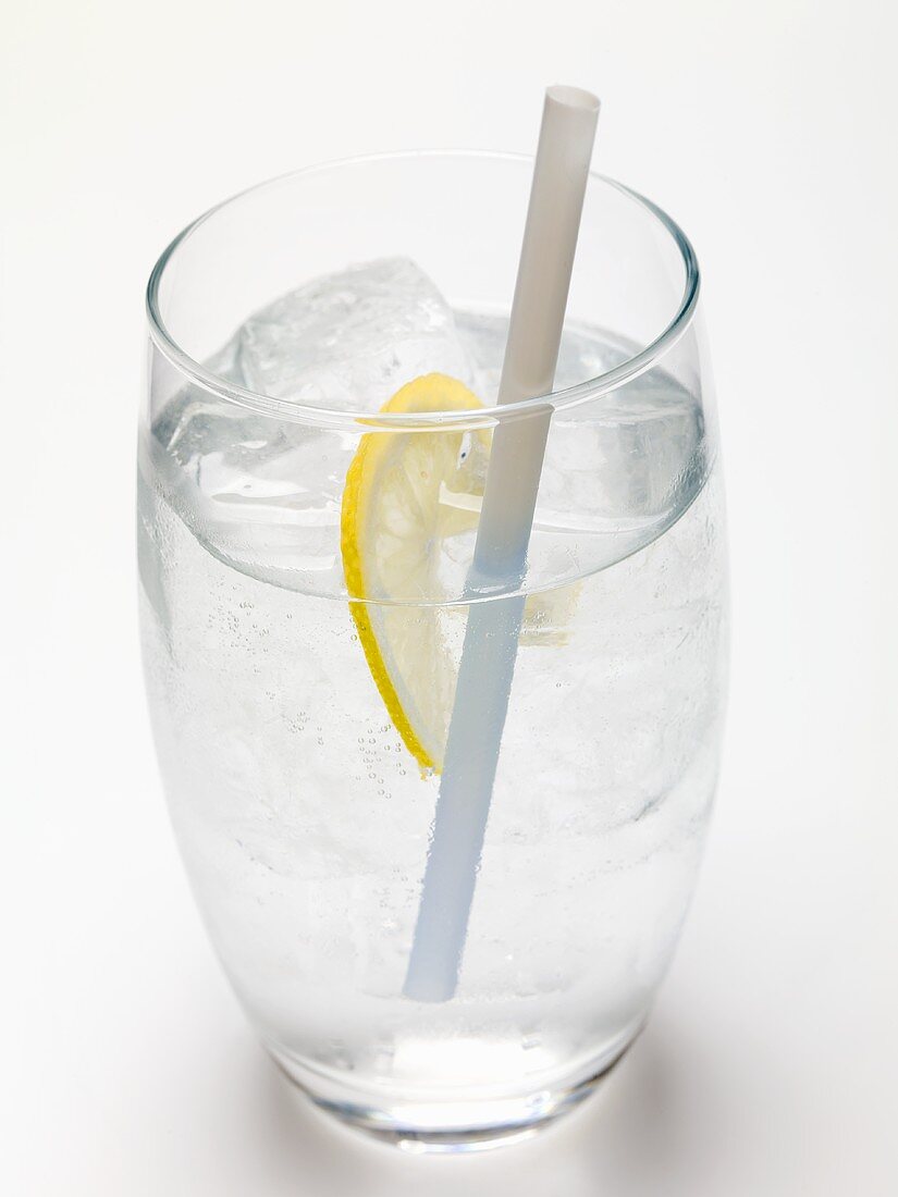 Glass of water with ice cubes, lemon and straw