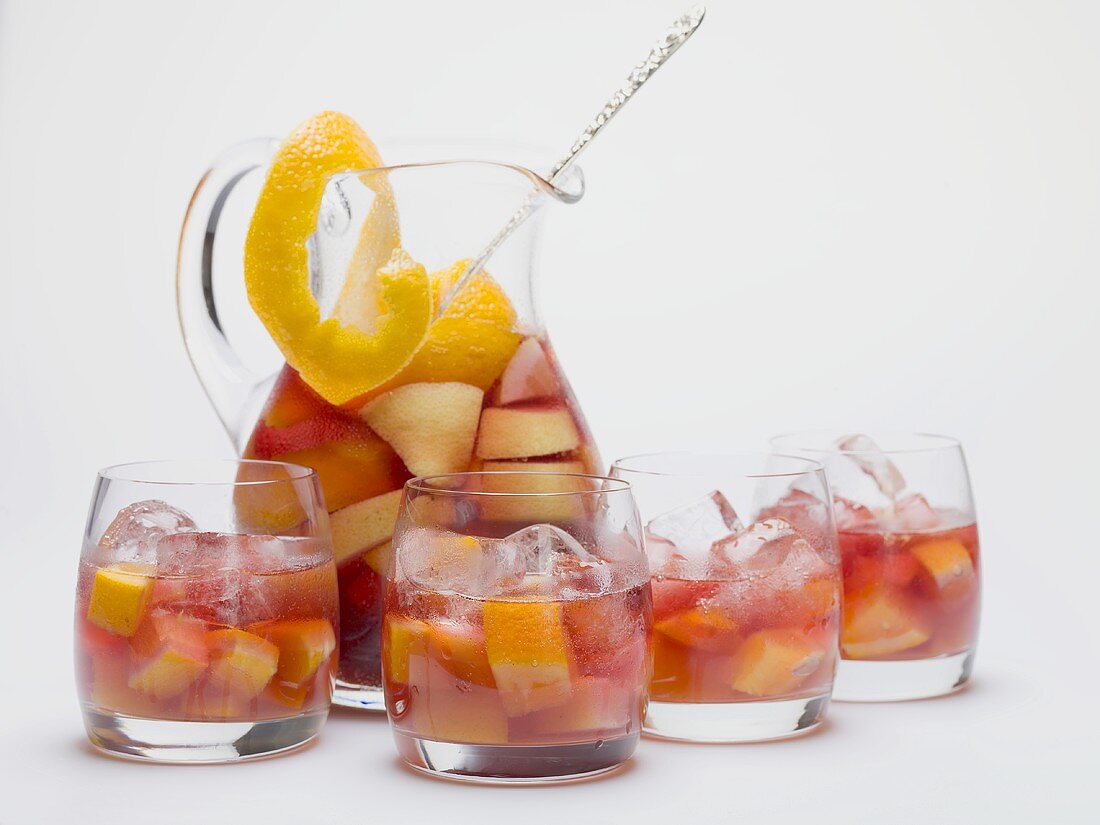 Fruity red wine punch in glass jug and glasses