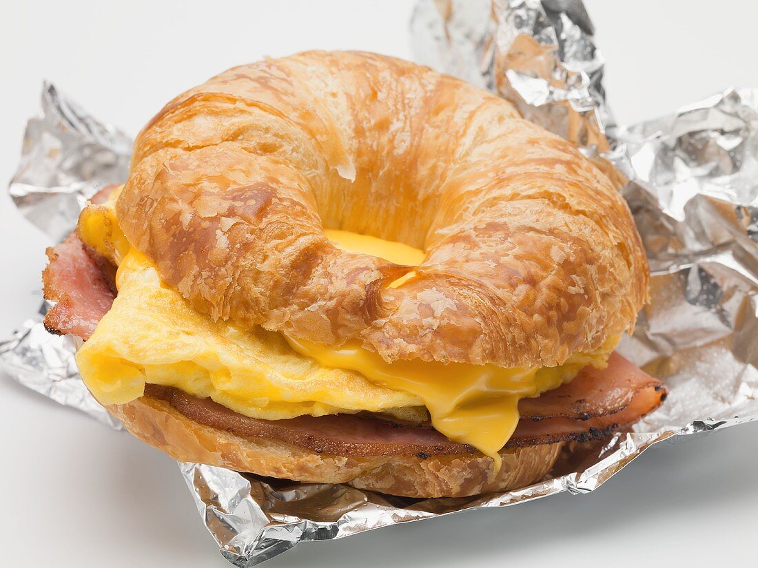 Croissant filled with scrambled egg, cheese & bacon on foil