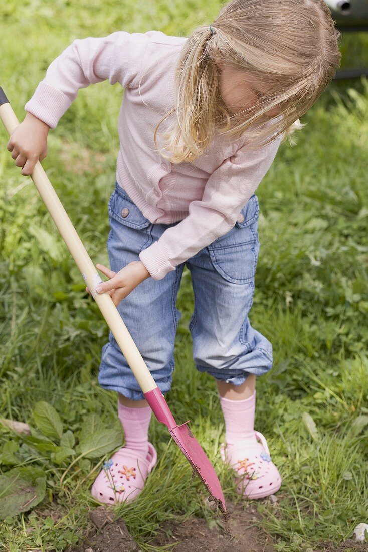 Kleines Mädchen mit Schaufel bei der Gartenarbeit