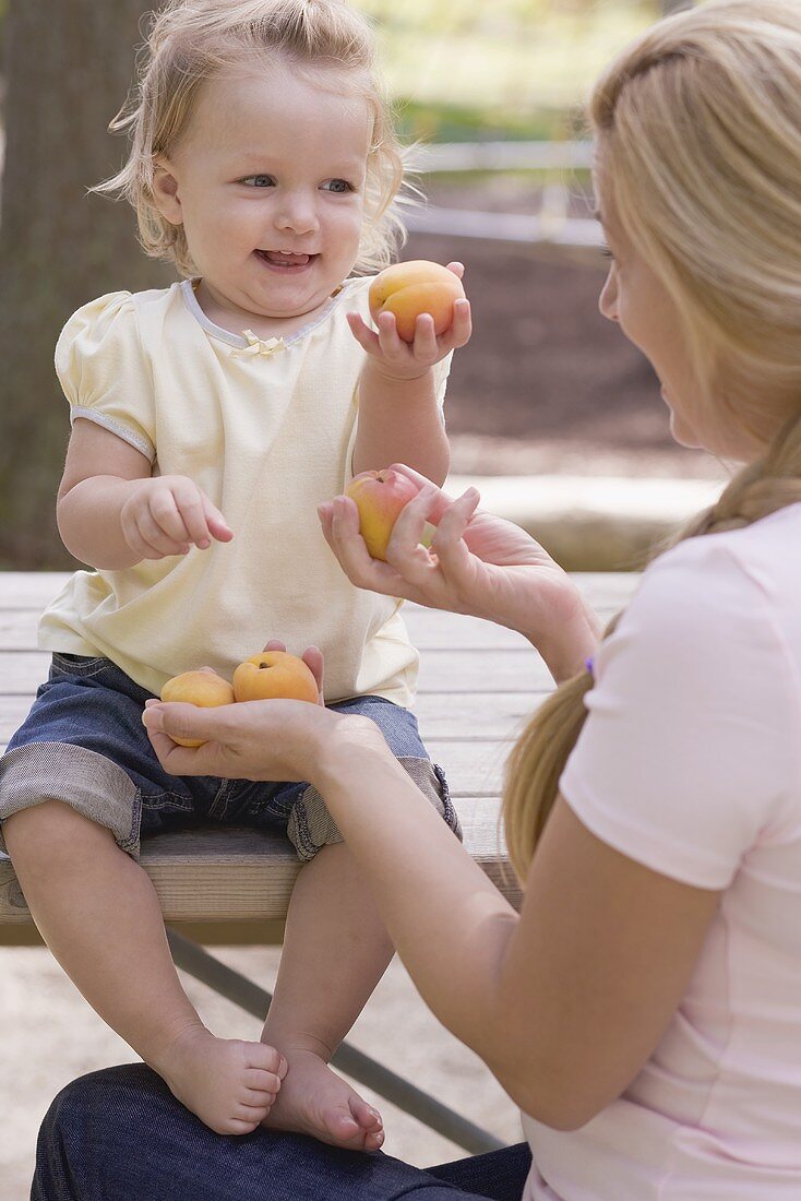 Mutter und kleine Tochter halten frische Aprikosen