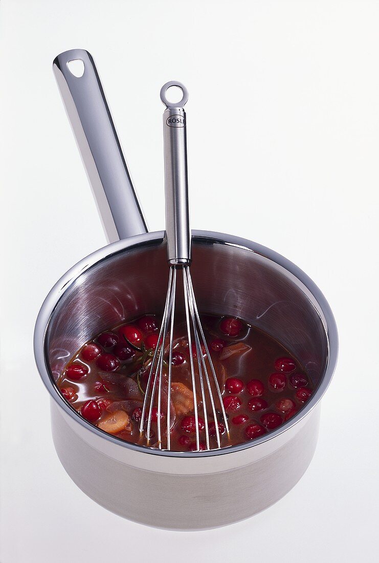 Cranberry-Rotweinsauce in einem Topf mit Schneebesen