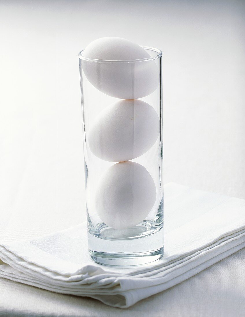 Three hens' eggs in a glass