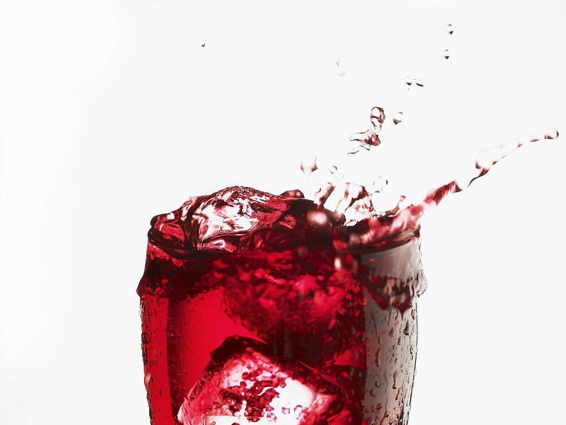 Cranberry juice splashing out of a glass