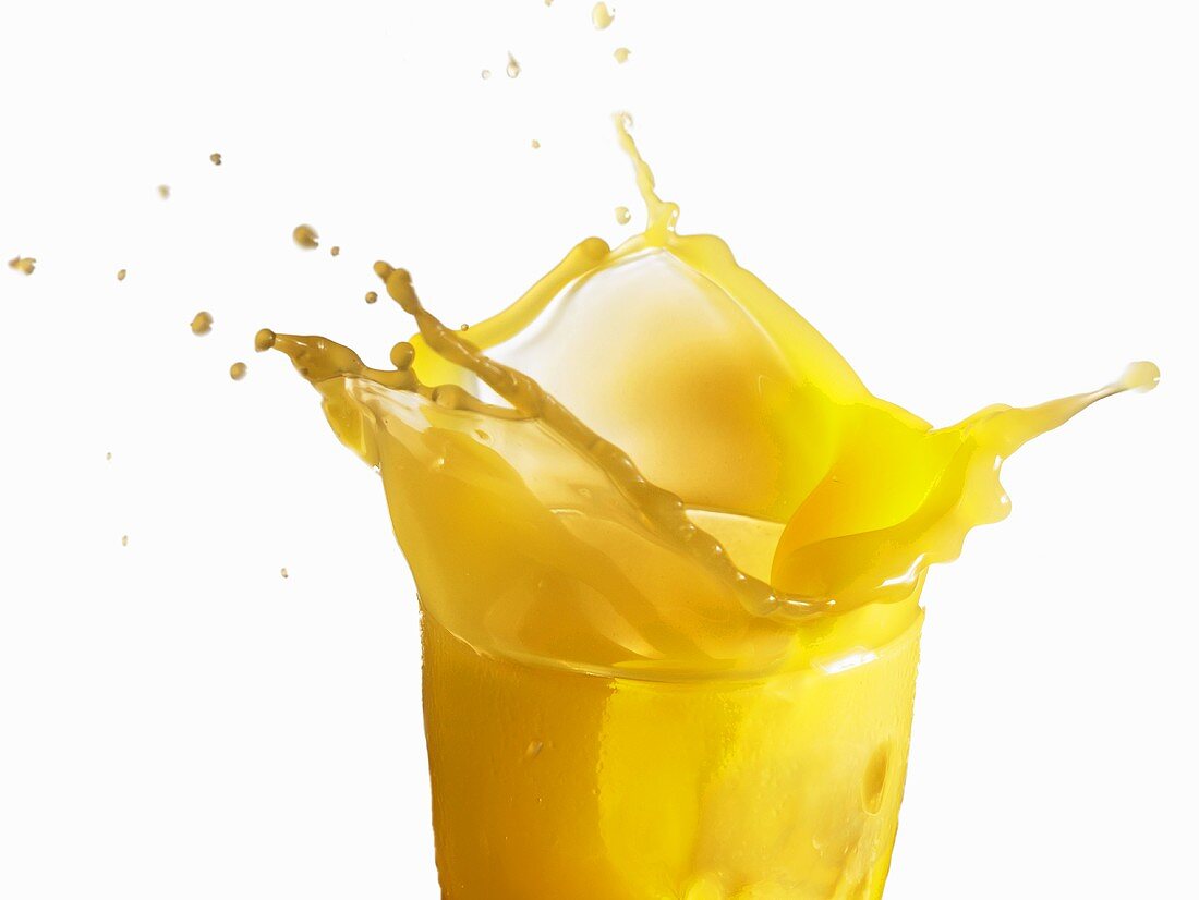 Orange juice splashing out of a glass
