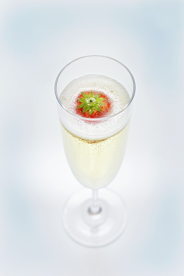 A glass of sparkling wine with strawberry