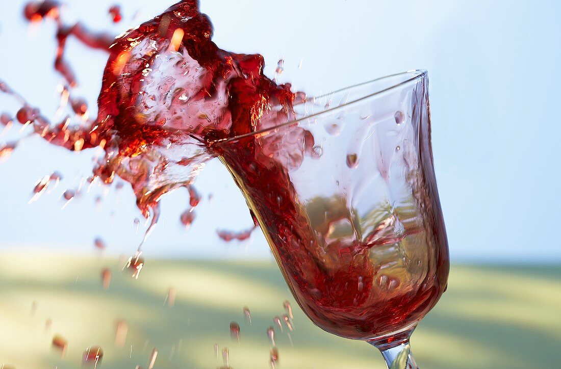 Rotwein spritzt aus dem Glas