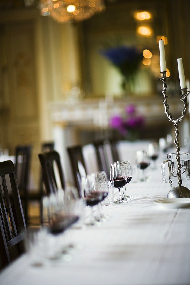 Table laid in white with glasses of red wine