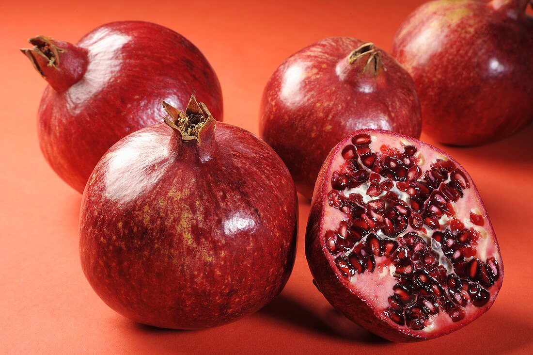 Several pomegranates, whole and halved