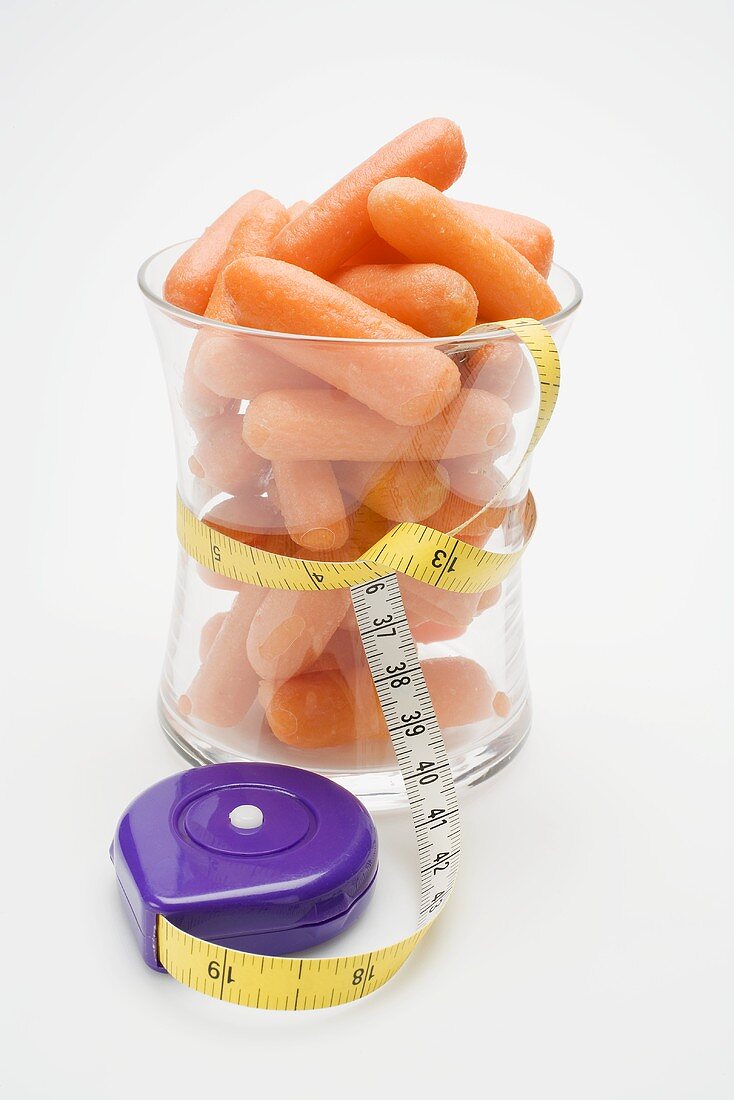 Baby carrots in glass with tape measure around it