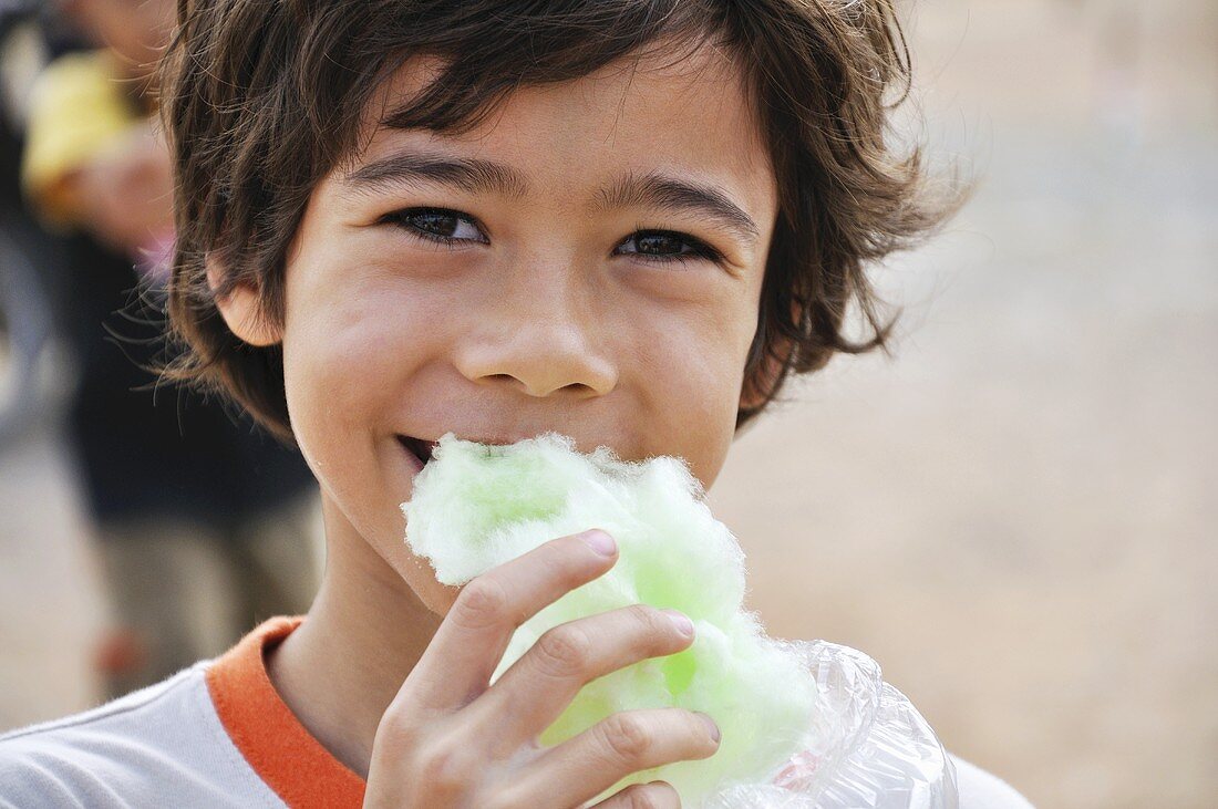 Kleiner Junge isst grüne Zuckerwatte