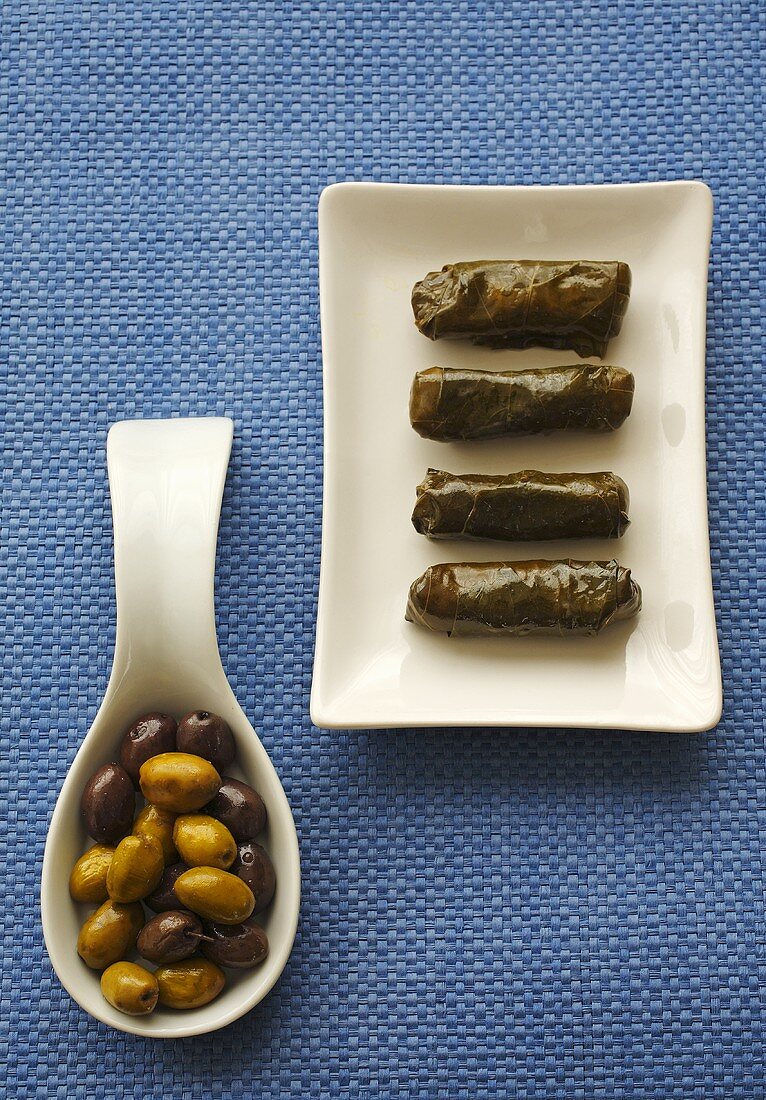Gefüllte Weinblätter auf Teller, Oliven auf Löffel