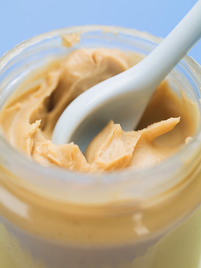 Erdnussbutter im Glas mit Löffel (Close Up)