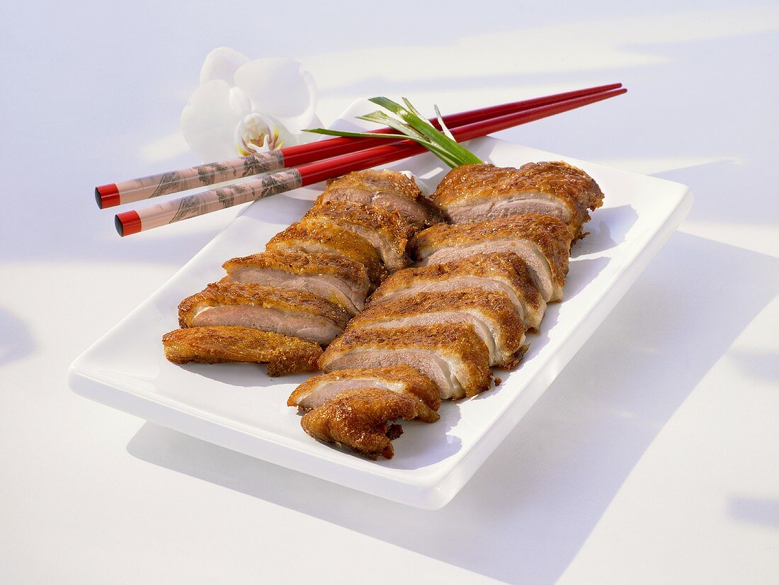 Sliced duck breast on plate with chopsticks
