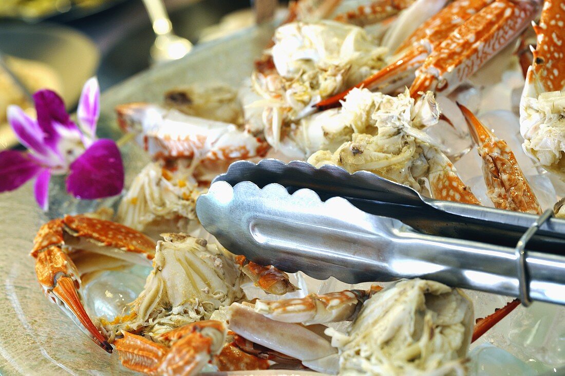 Pieces of crab on ice with tongs