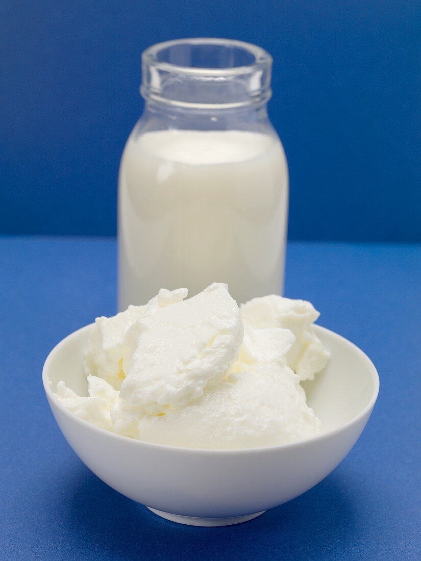 Quark in small white bowl in front of bottle of milk