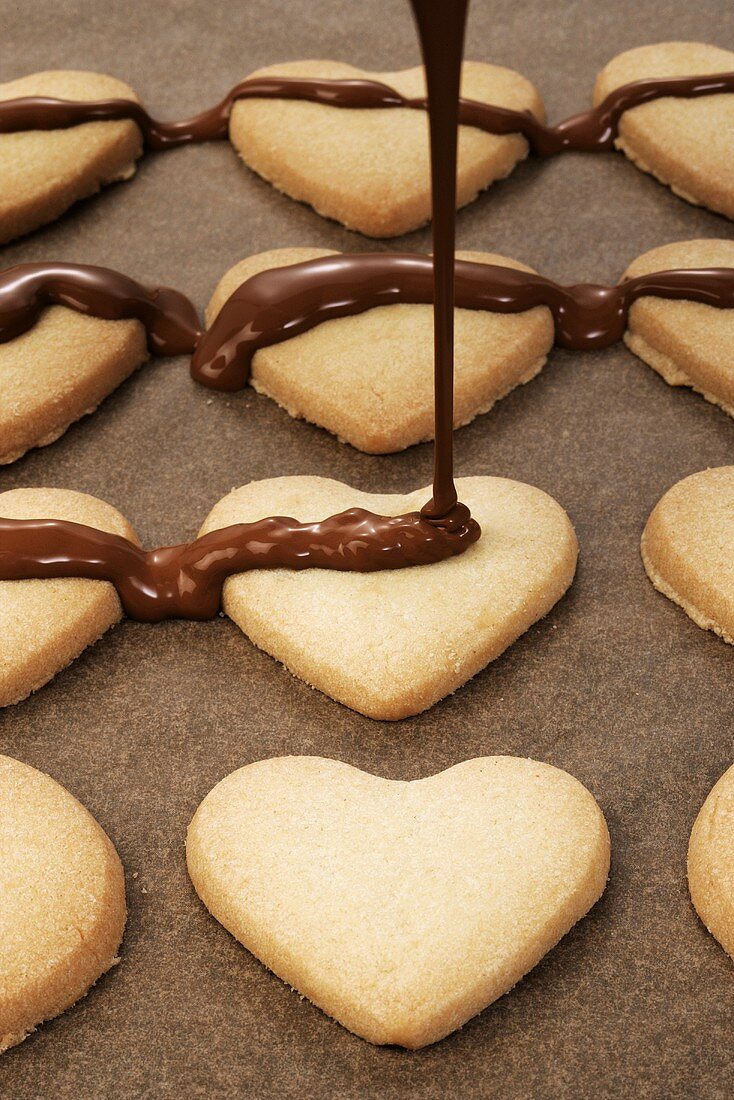Decorating heart-shaped biscuits with couverture chocolate