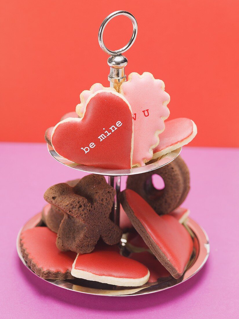 Heart-shaped biscuits with pink & red icing & chocolate cakes