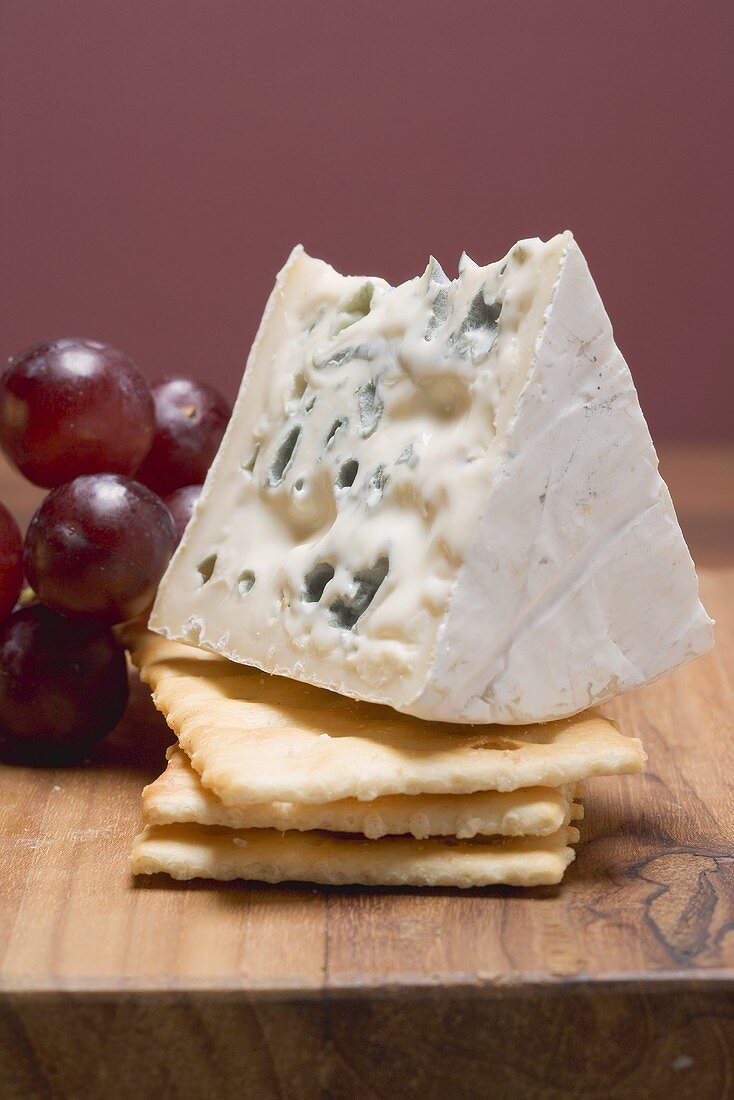 Stück Blauschimmelkäse mit Crackern und roten Trauben