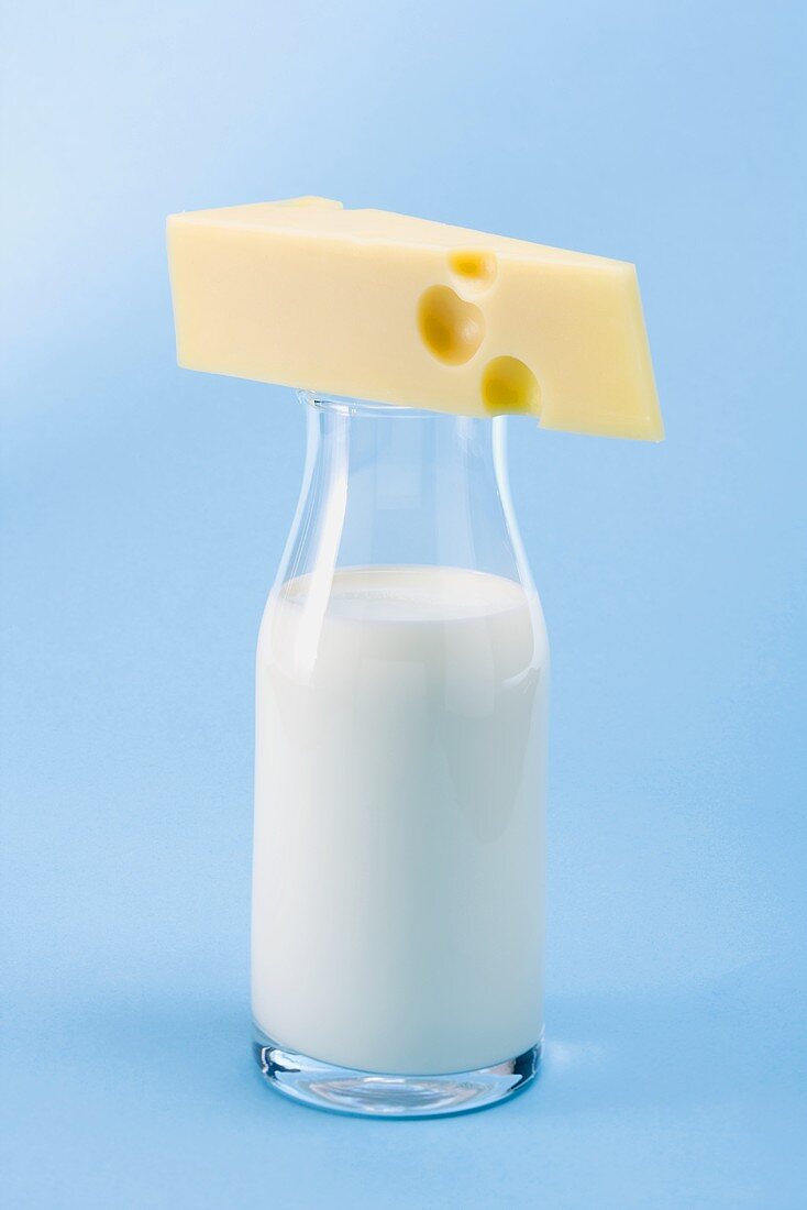 Piece of Emmental cheese on bottle of milk