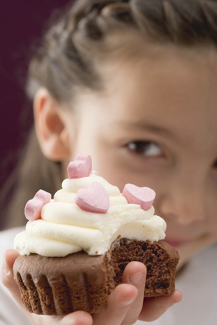 Kleines Mädchen hält Cupcake mit Zuckerherzen