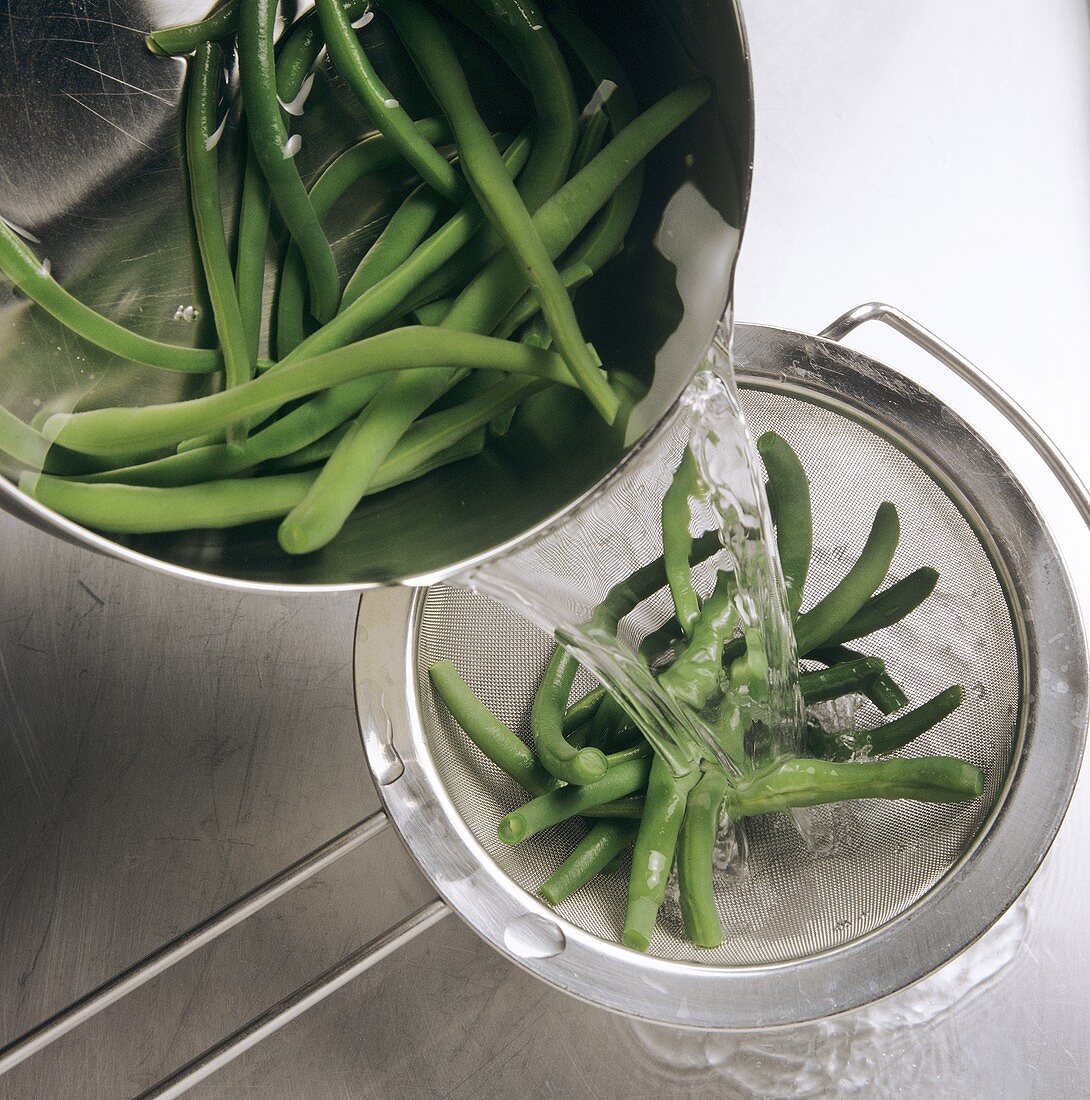 Straining blanched green beans through a sieve