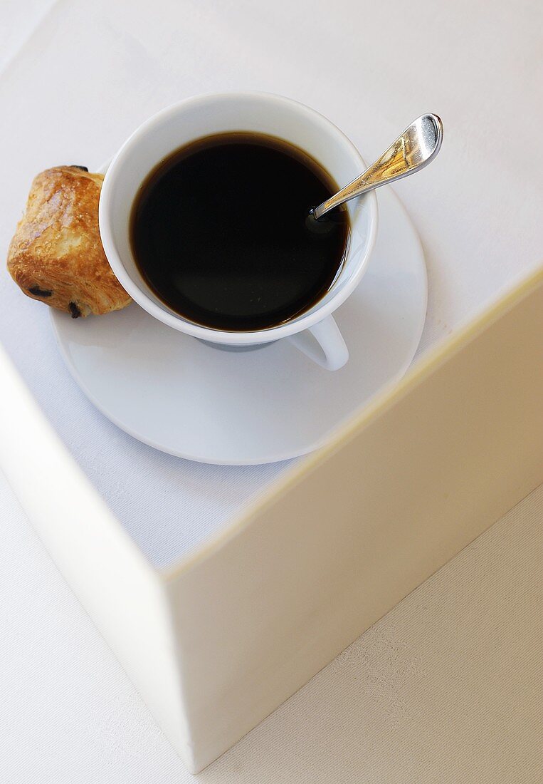 Tasse schwarzer Kaffee mit Gebäck auf Untertasse
