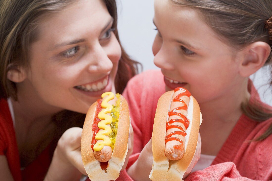 Woman and girl laughing and eating hot dogs