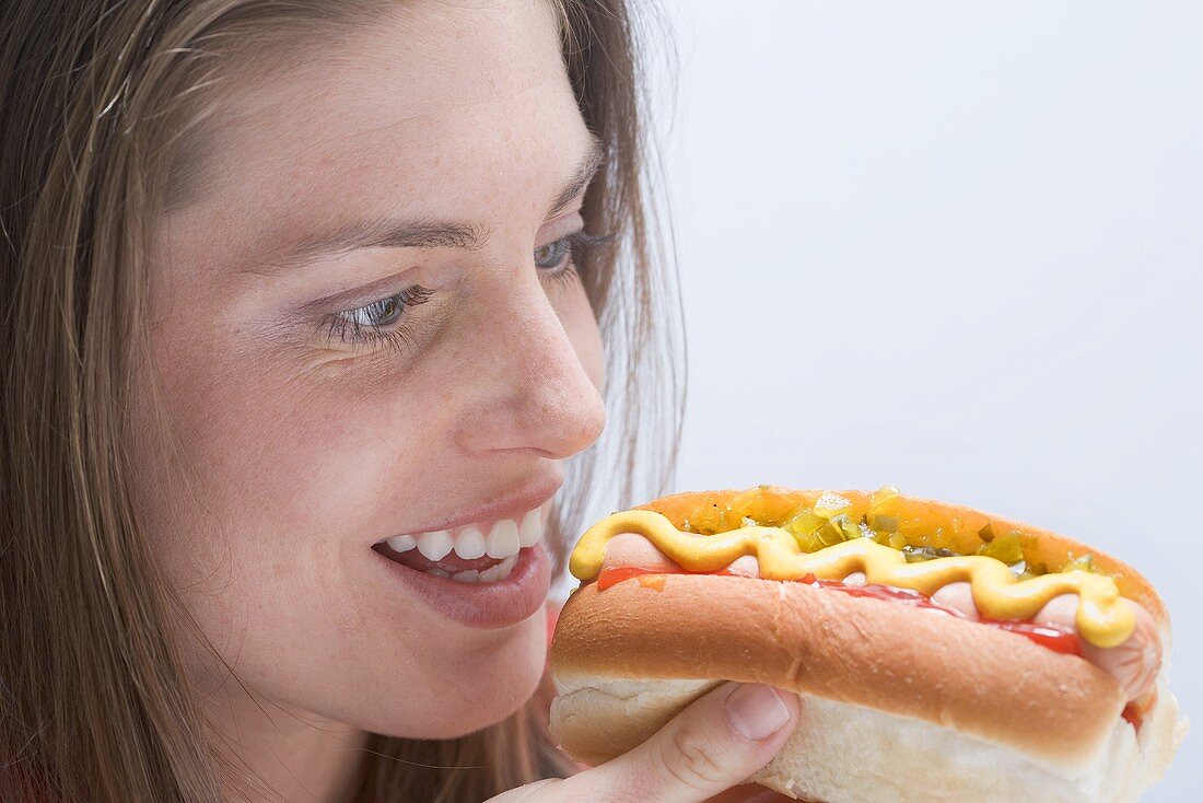Junge Frau einen Hot Dog betrachtend
