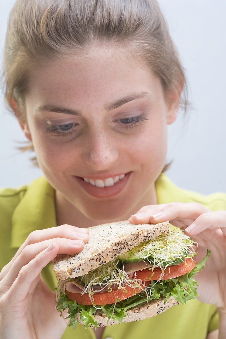 Junge Frau mit Sandwich in den Händen